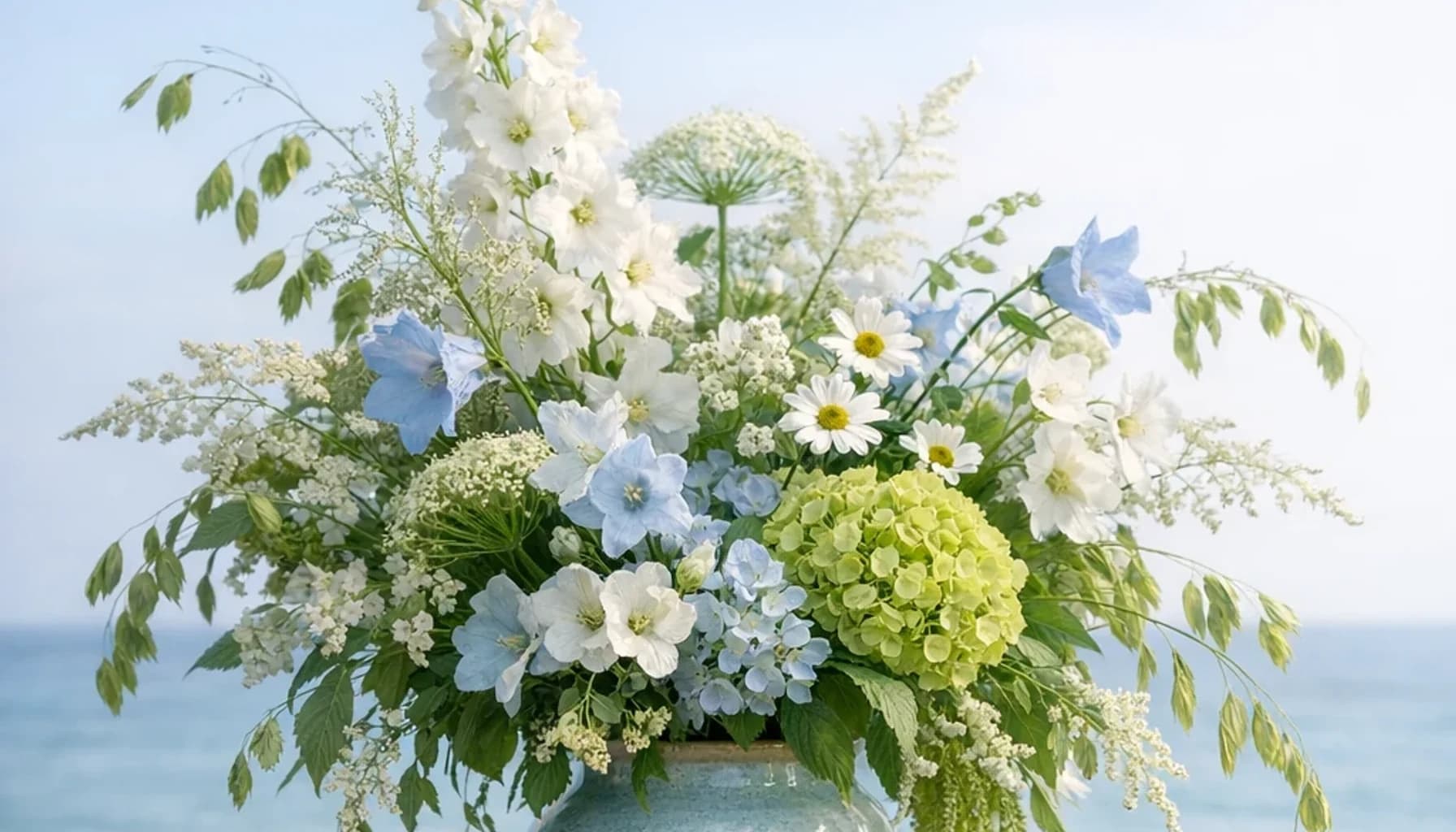 World Oceans Day flower guide banner featuring seasonal wildflowers, green hydrangea, textural foliage in leaf, moss, sky, clay tones