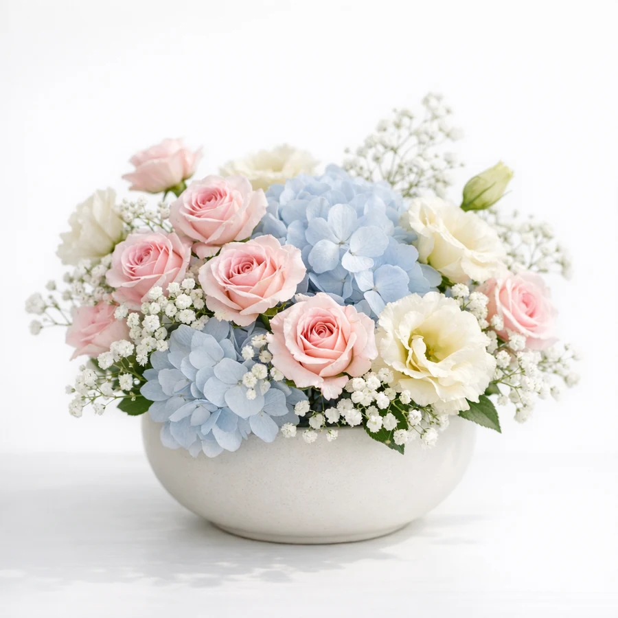 Soft pastel new baby floral arrangement with pale pink spray roses, powder blue hydrangea, and cream lisianthus in a round ceramic bowl