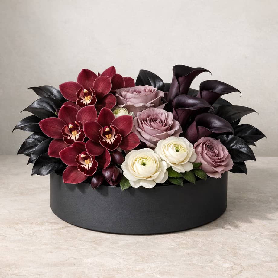 Orchid Nocturne flower box with burgundy cymbidium orchids, plum calla lilies, mauve roses, and ivory ranunculus