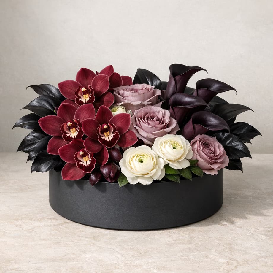 Orchid Nocturne flower box with burgundy orchids, plum calla lilies, mauve roses, and ivory ranunculus