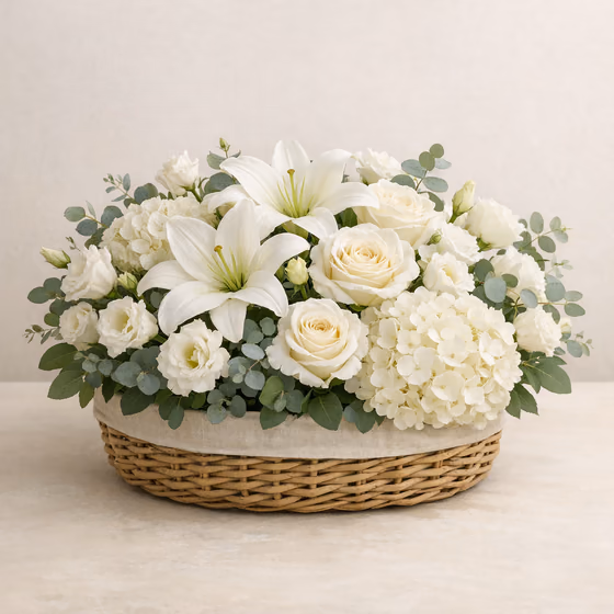 Graceful Tribute white sympathy basket with lilies, roses, hydrangea, lisianthus, and eucalyptus