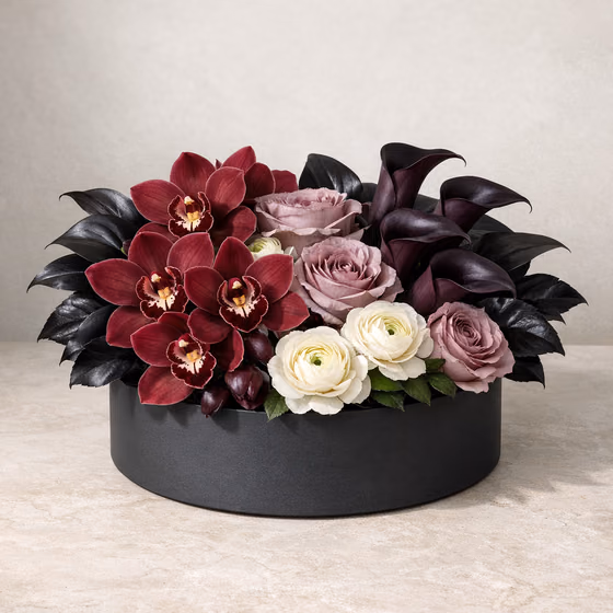 Orchid Nocturne flower box with burgundy cymbidium orchids, plum calla lilies, mauve roses, and ivory ranunculus